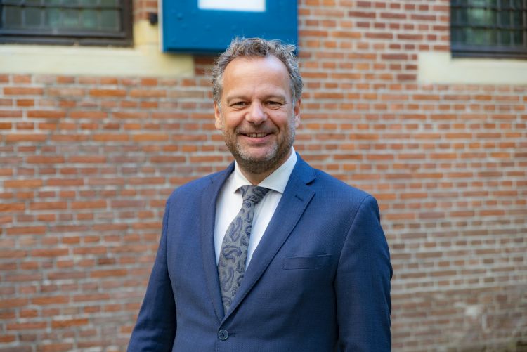 Portretfoto van wethouder Rick Verschure, buiten voor een muur