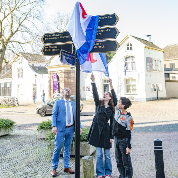Jaiden en Stella verwijderen onder toeziend oog van wethouder Rick Verschure de Zutphense vlag van de bewegwijzering met het nieuwe ornament