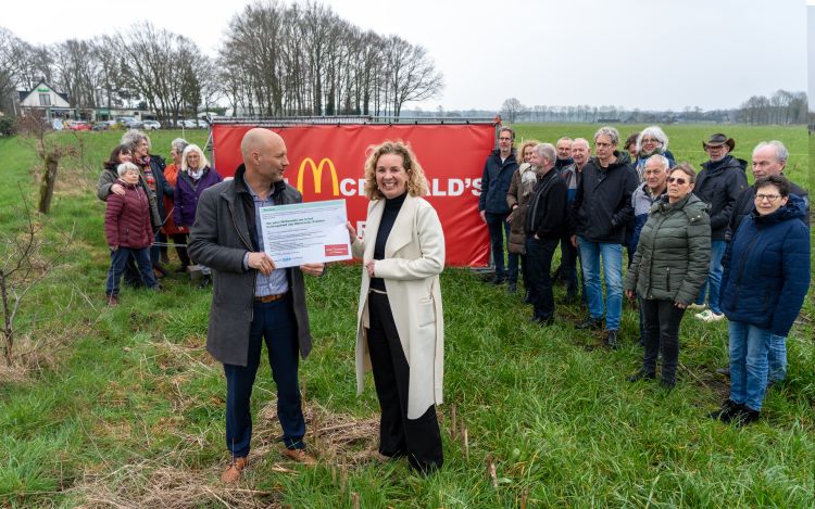 Omwonenden van 't Ooievaarsnest met wethouder Bloem die de petitie vasthoudt, voor een spandoek tegen de komst van McDonald's.