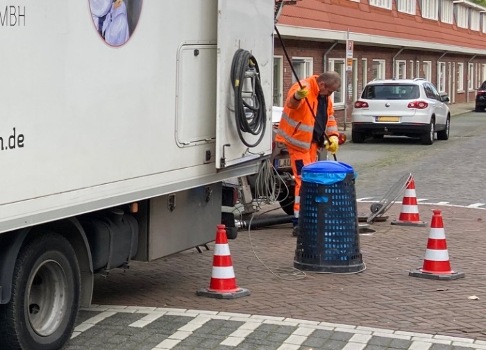 Medewerker aan het werk. Kabel met onder andere camera gaat via rioolput naar binnen.