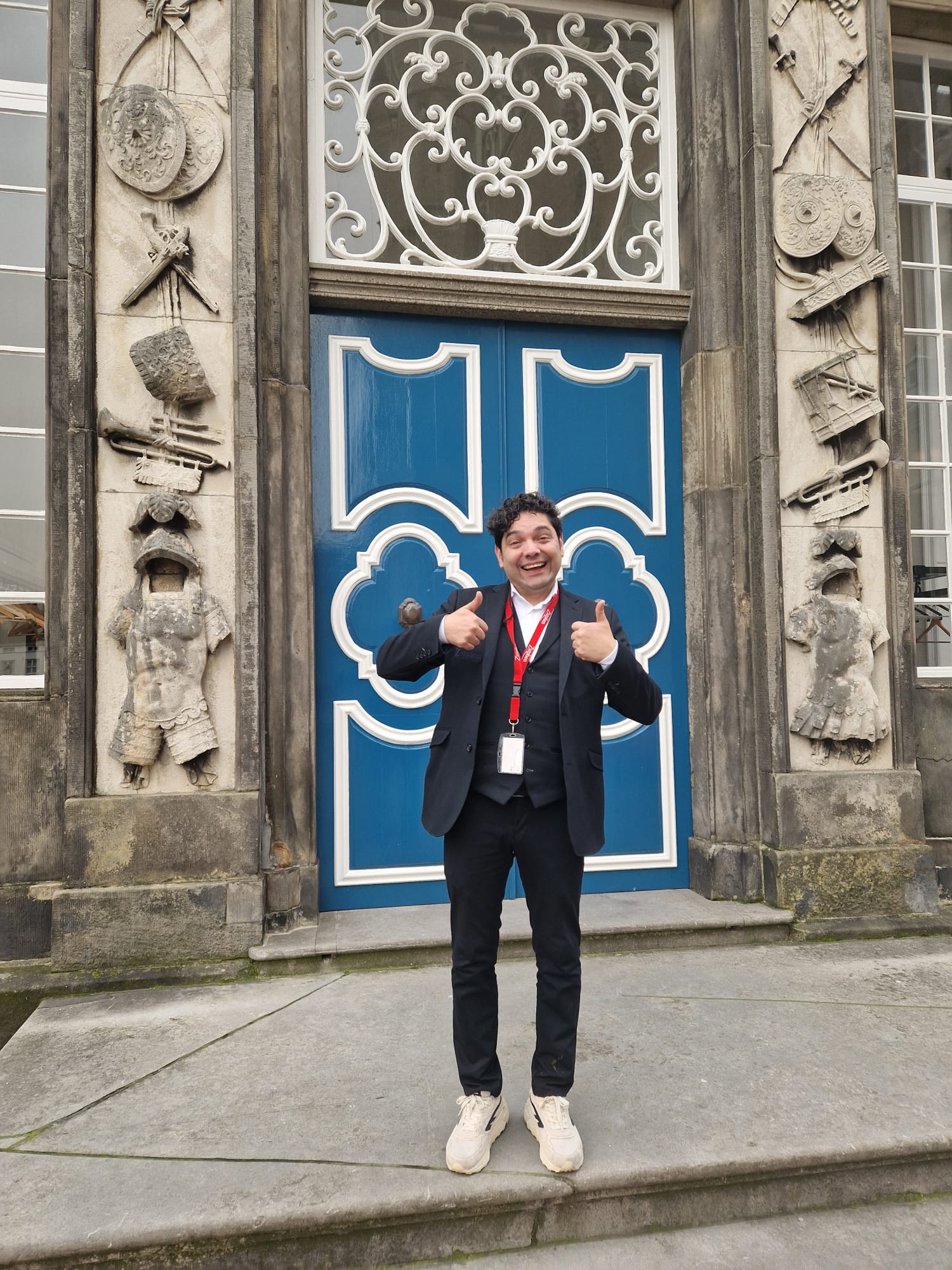 Alejandro staat lachend voor het oude stadhuis en steekt zijn duimen omhoog.